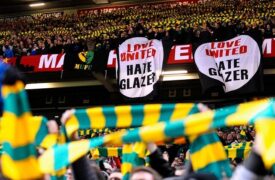 Οι φίλαθλοι της Μάντσεστερ Γιουνάιτεντ κρατώντας τα κασκόλ στα πρώτα χρώματα του συλλόγου